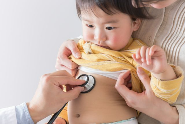 医師の聴診を受ける、母親に抱かれた子供