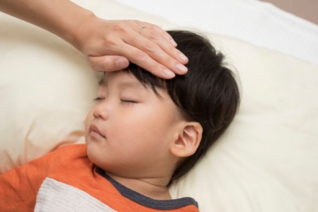 おでこに手を当てられ眠る男の子
